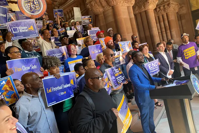 Dozens of people carrying signs that say "pass Clean Slate" and "end perpetual punishment" hold a rally at the ornate Million Dollar Staircase at the state Capitol in Albany